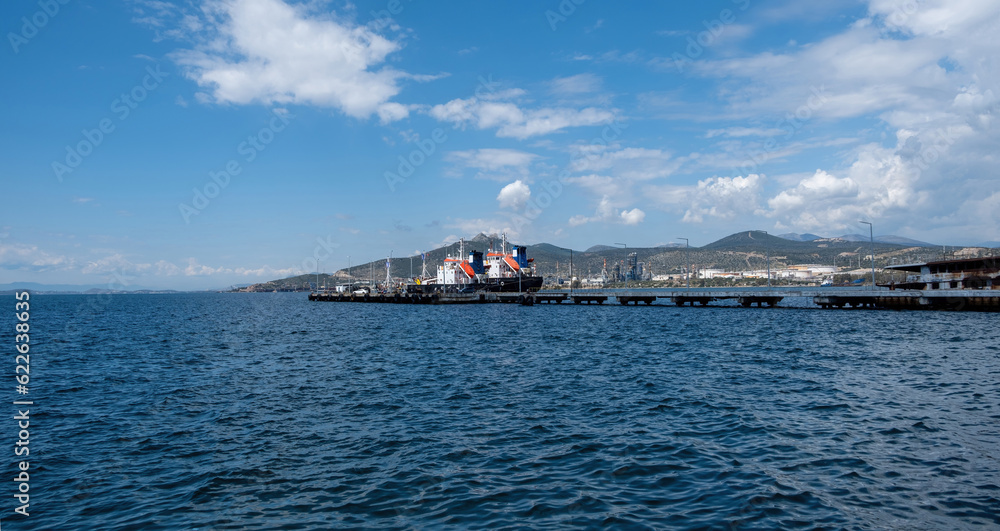 Elefsina Attica Greece. Moored ship at harbor in rippled sea opposite  Petroleum Oil Refinery.