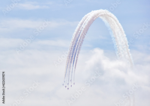 british raf red arrows falcons aerobatic team fighter jet with blue skies in formation with white and blue smoke trail air show display teams curve