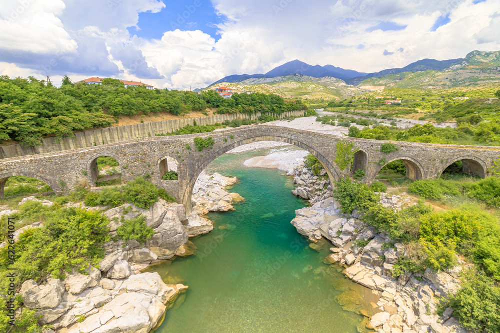 Mesi Bridge in Albania is stunning architectural wonder that spans Kir River in a quaint village. This historic stone bridge, originating from Ottoman era, brings a sense of heritage to surroundings.