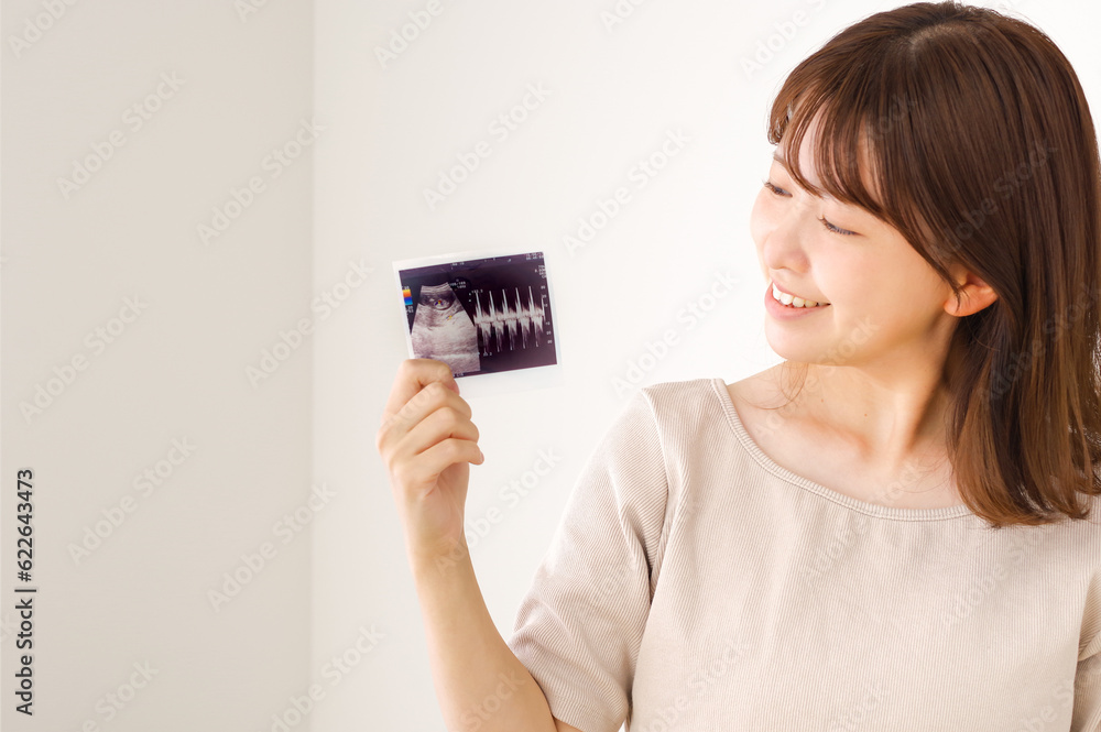 妊娠検査のエコー写真を持つ若い女性
