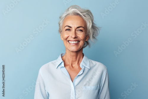 Portrait of happy senior woman looking at camera and smiling while standing against blue background photo