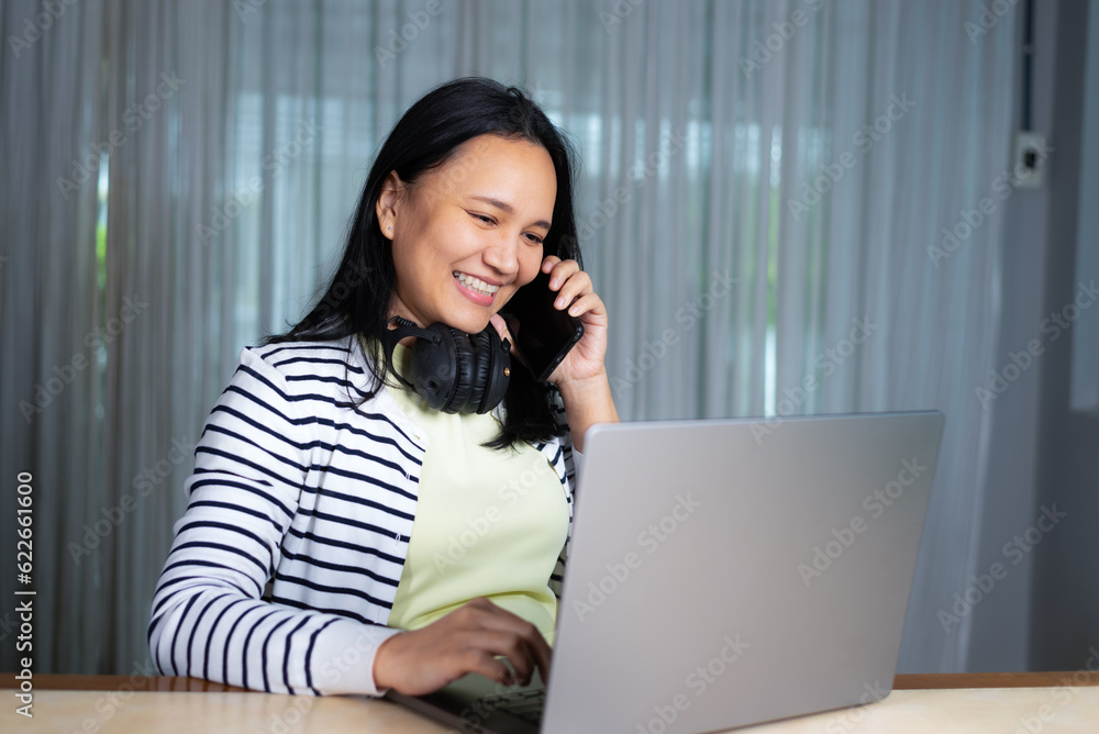 Smiling woman on call while working on laptop in casual clothing at home Smiling woman on call while working on laptop in casual clothing at home