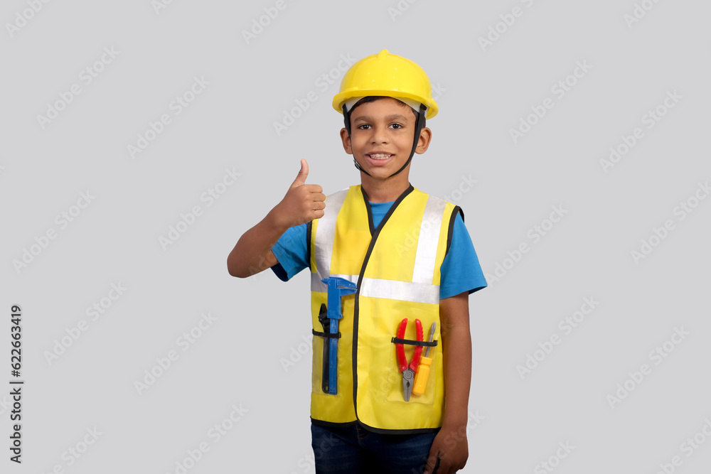 Future architect Indian Boy wearing construction manager uniform and helmet showing thumbs up Future architect Indian Boy wearing construction manager uniform and helmet showing thumbs up
