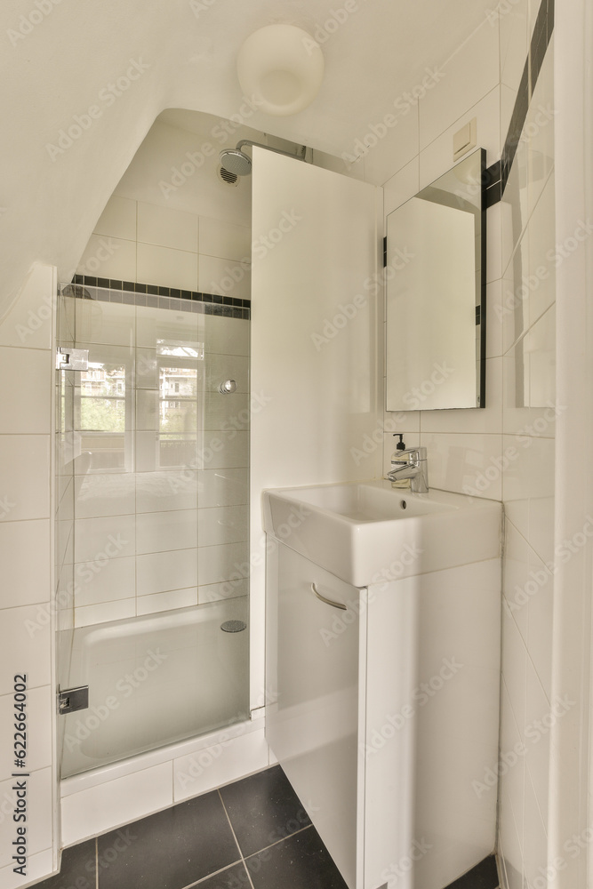 a white bathroom with black tile flooring and a mirror on the wall above the sink in the shower stall a white bathroom with black tile flooring and a mirror on the wall above the sink in the shower stall