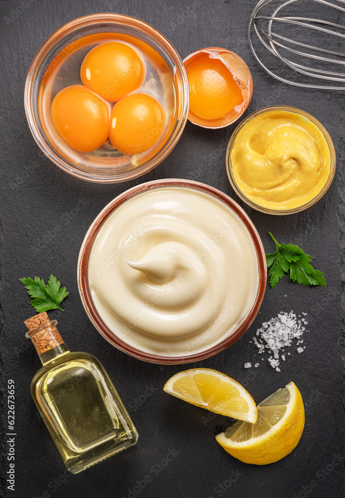 Homemade mayonnaise and mayo ingredients on black stone slate serving plate. Flat lay. Homemade mayonnaise and mayo ingredients on black stone slate serving plate. Flat lay.
