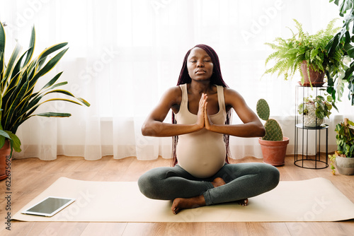 Black pregnant woman meditating during yoga practice © Drobot Dean