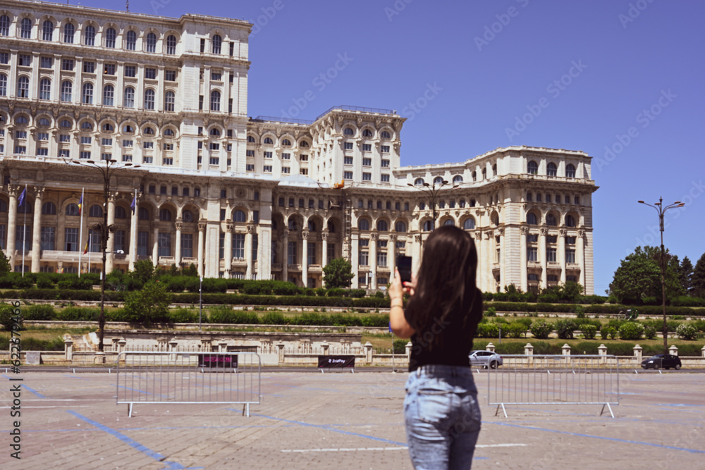   Bucharest ,Romania Constitution Square.  Young beautiful smiling  woman  using a mobile phone taking a pictures.Concept of Romanian gastronomy and travel