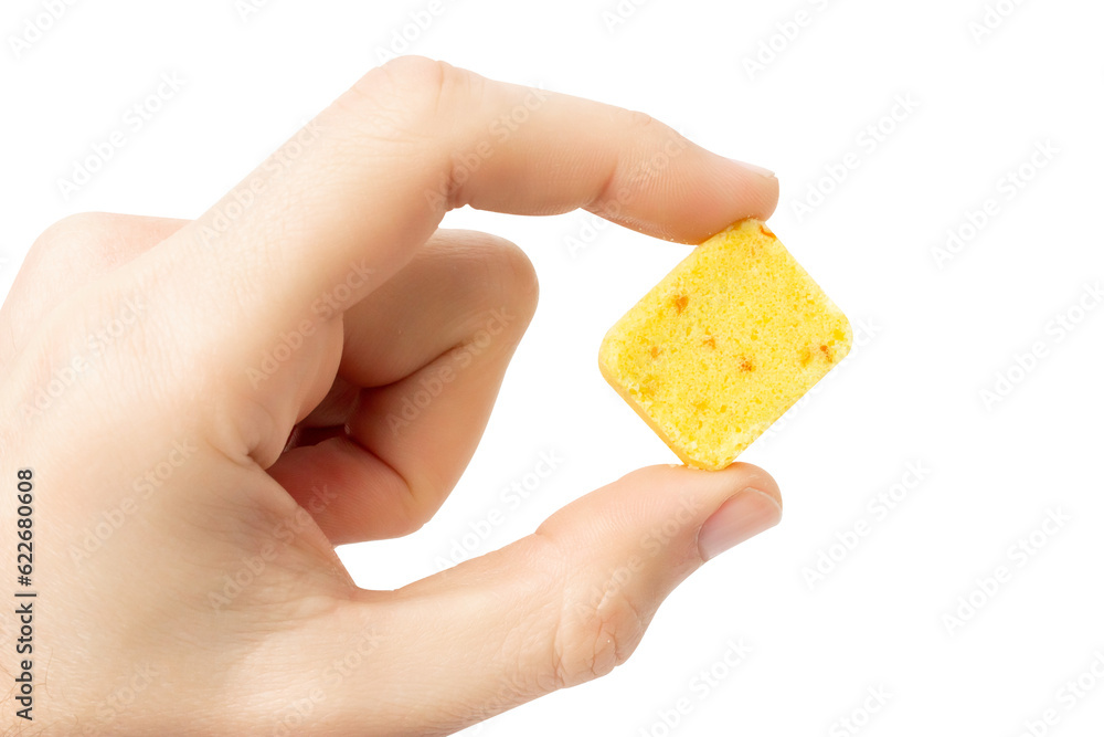 Yellow bouillon cube in hand. Isolate on a white background. Yellow bouillon cube in hand. Isolate on a white background.