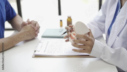 Young Asian dentist explaining patient's endodontic treatment, discussing dental treatment plan in dental clinic office - dentist consultation concept