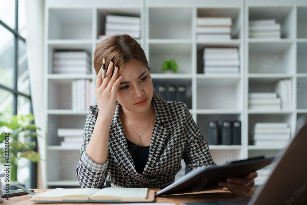Portrait of business owner, woman using computer and financial statements Anxious expression on expanding the market to increase the ability to invest in business Portrait of business owner, woman using computer and financial statements Anxious expression on expanding the market to increase the ability to invest in business
