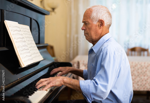 Man practicing playing piano in the living room of his home after retirement from work