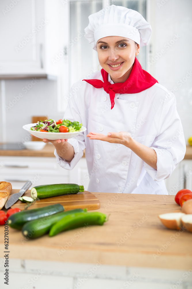 Portrait of positive woman chef presenting salad Portrait of positive woman chef presenting salad