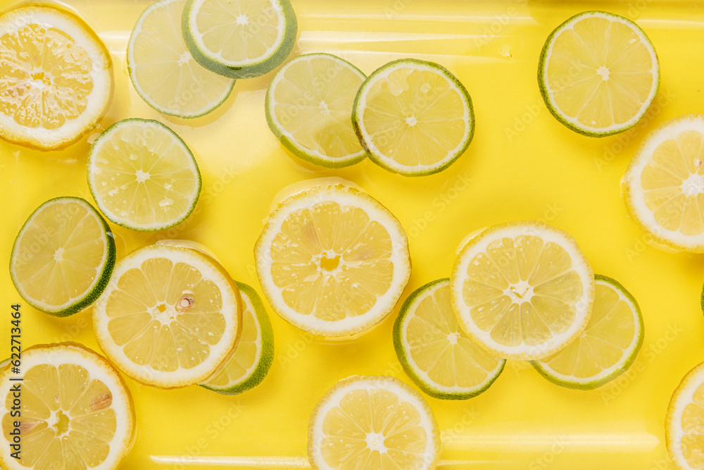 lemon and lime slices in water on yellow background lemon and lime slices in water on yellow background