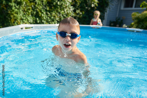 8 year old boy dives out of the pool wearing swimming goggles