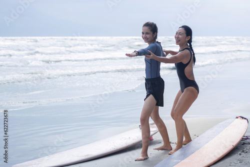 Photography Pretty teen girl learning to surf with woman instructor, surfing lessons on the