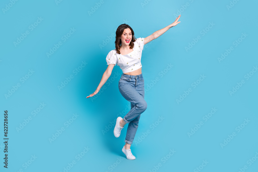 Full length photo of adorable carefree girl dressed white top flying arms sides isolated blue color background