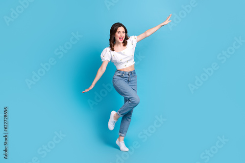 Full length photo of adorable carefree girl dressed white top flying arms sides isolated blue color background © deagreez