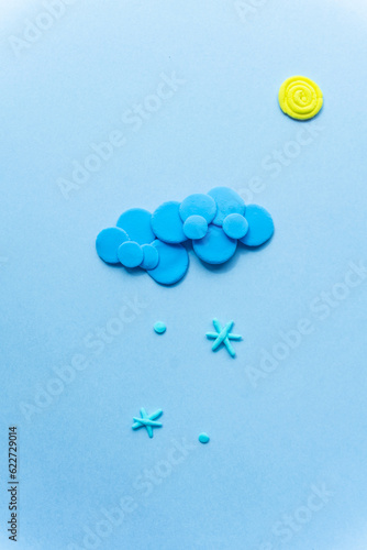 Plasticine sun with cloud. Modeling clay handmade weather on blue background.