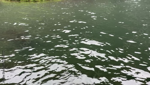 Tilt up camera from water to reveal waterfall with slight mist rolling above the water. 