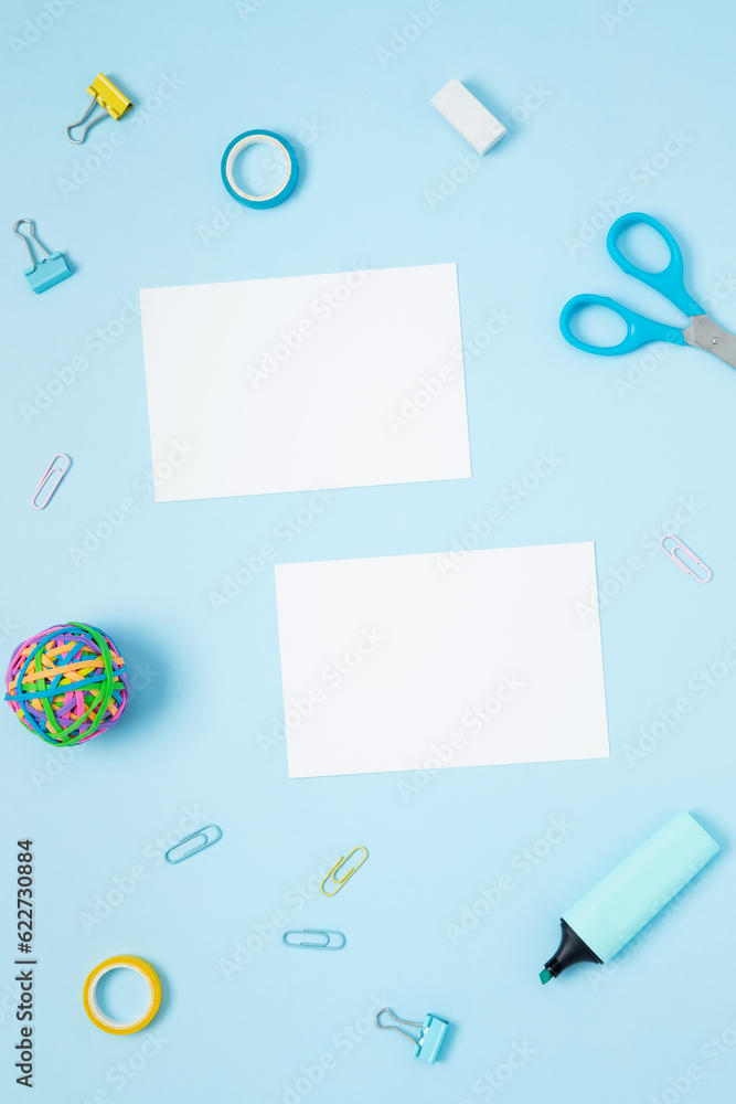 Mockup white papers and set of stationery for work and study on blue background. Back to school. Top view, flat lay, copy space Mockup white papers and set of stationery for work and study on blue background. Back to school. Top view, flat lay, copy space