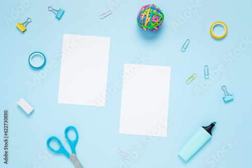 Mockup white papers and set of stationery for work and study on blue background. Back to school. Top view, flat lay, copy space