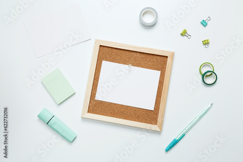 Creative flat lay mockup design of workspace. Top view composition with cork board white paper and stationery on white background