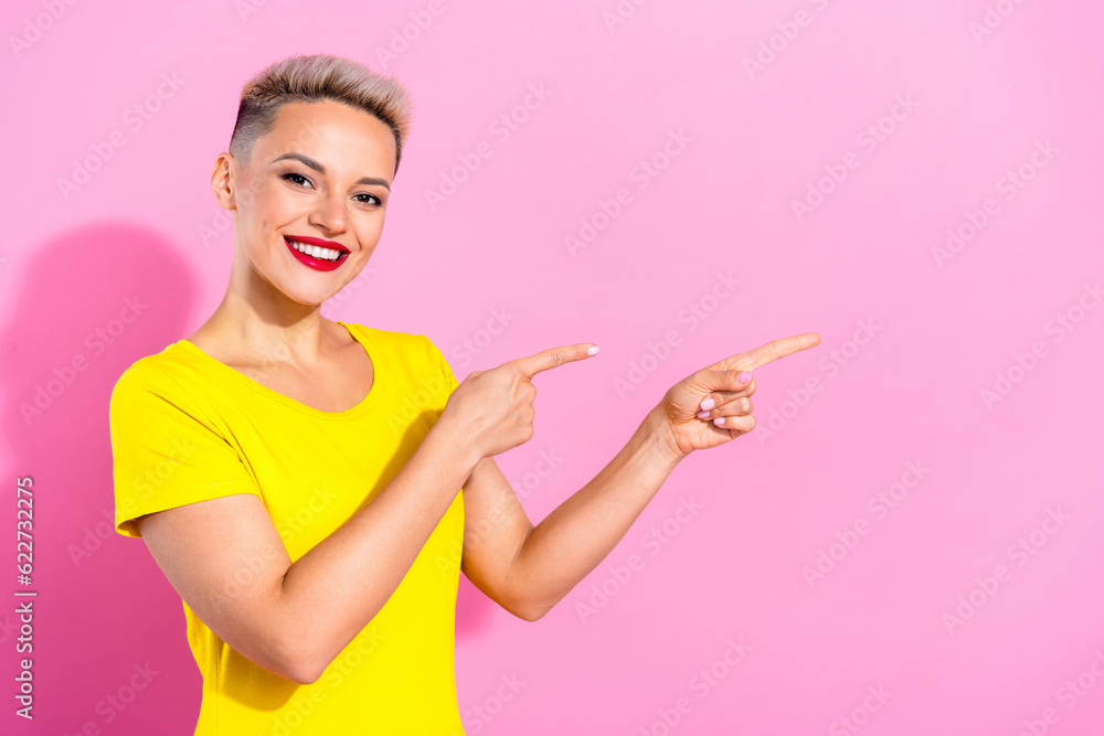 Photo of cheerful lovely person beaming smile indicate fingers empty space isolated on pink color background Photo of cheerful lovely person beaming smile indicate fingers empty space isolated on pink color background