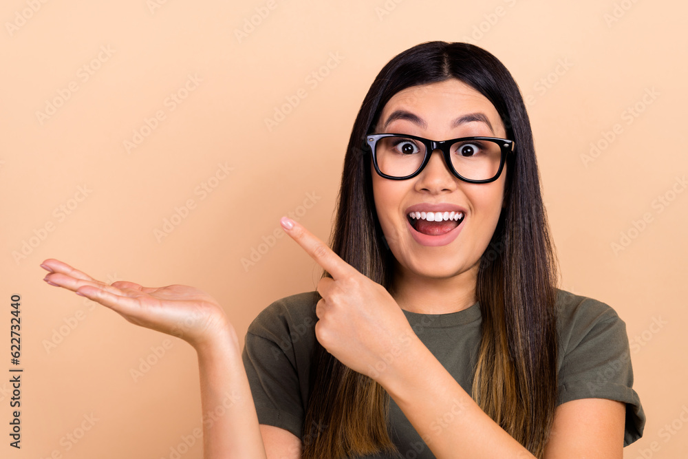 Portrait of positive impressed person open mouth indicate finger hand hold empty space promo isolated on beige color background Portrait of positive impressed person open mouth indicate finger hand hold empty space promo isolated on beige color background