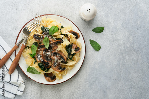 Creamy Alfredo pasta. Italian pasta fettuccini with mushrooms  chicken meat  spinach  basil and cream sauce on grey stone or concrete background. Traditional Italian cuisine. Flat lay. Copy space