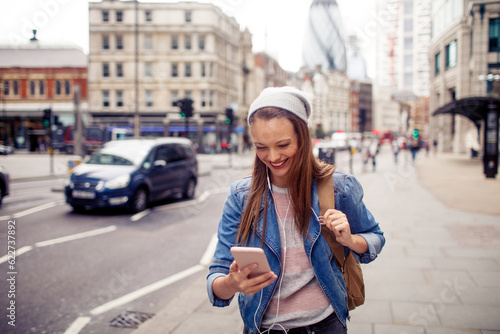 Young woman using a phone while walking in the city london © Geber86