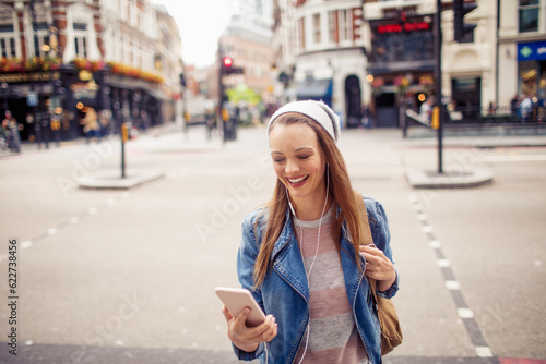 Young woman using a phone while walking in the city london