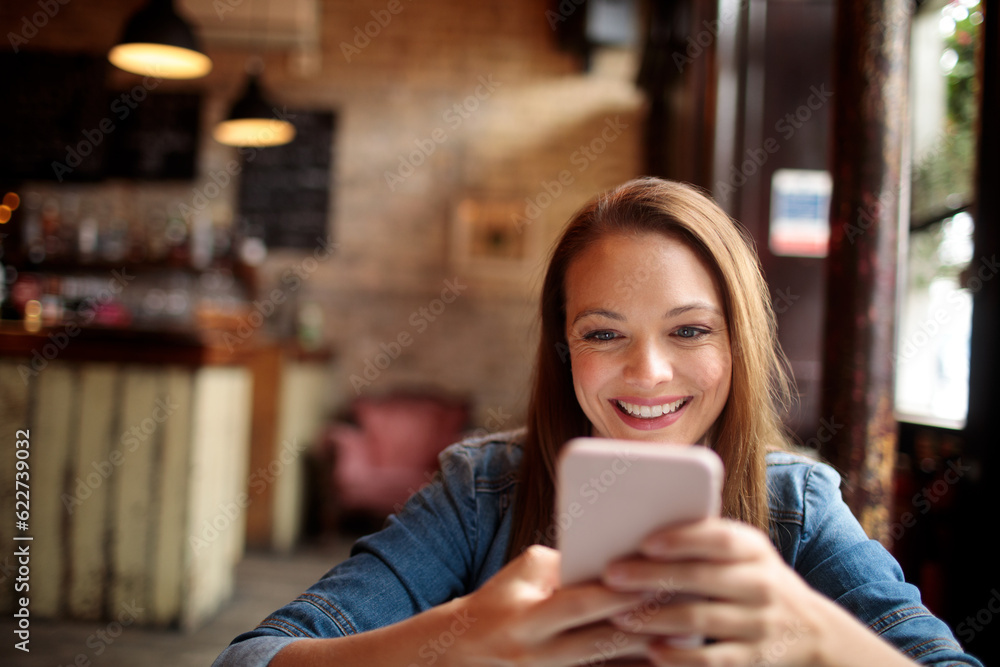 Young woman using a smart phone while sitting in an indoor cafe Young woman using a smart phone while sitting in an indoor cafe