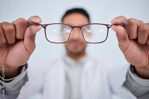 Hands, man and optician with glasses for vision, eyesight and eye care prescription lens. Closeup of doctor, optometrist and frame for eyewear, test and consulting for optical assessment in clinic