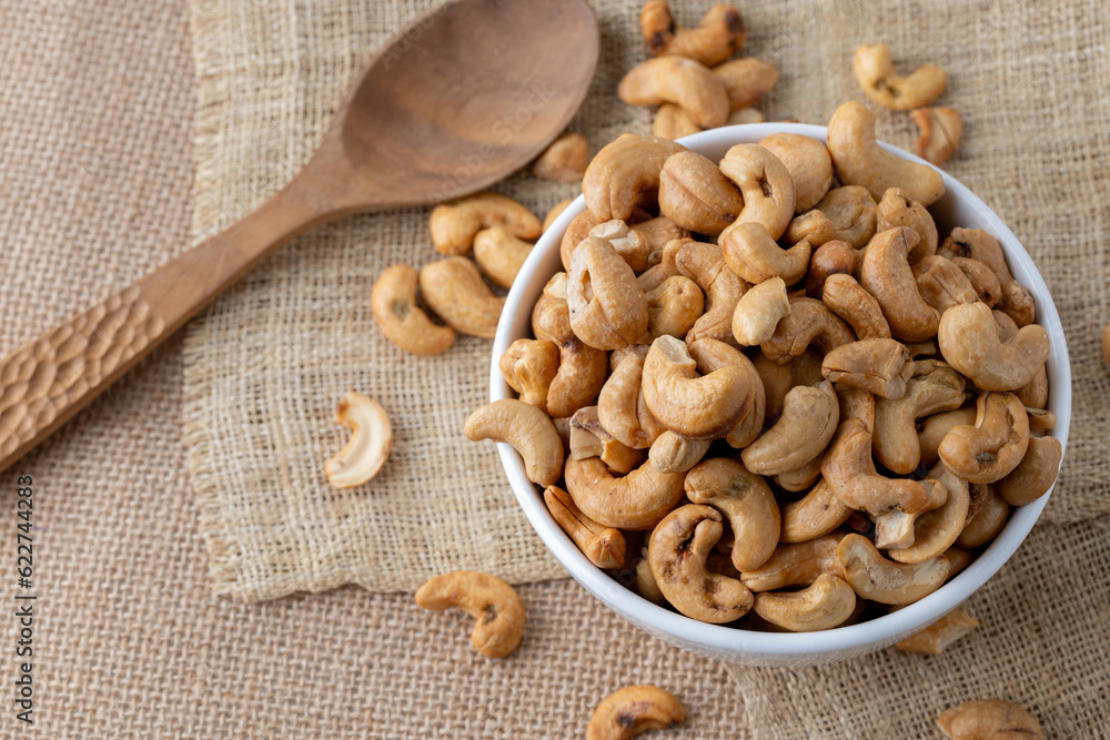 Roasted cashew nuts and halves in wooden bowl on table top view. Macro studio shot Homemade Roasted Salted Cashews in basket and spoon breakfast on sack, Healthy food Seeds snack product Roasted cashew nuts and halves in wooden bowl on table top view. Macro studio shot Homemade Roasted Salted Cashews in basket and spoon breakfast on sack, Healthy food Seeds snack product