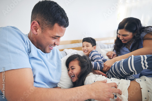 Family, tickle and play on bed with fun and smile in a home with bonding and parent care. Happy, house and bedroom with a father, mom and children together in the morning with dad, mother and kid © Azee/peopleimages.com