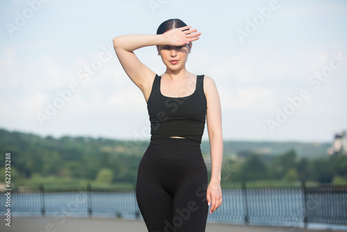 Young woman in black sportswear exercising outdoors. Fitness and healthy lifestyle concept. The white girl does sports in the park. © romeof