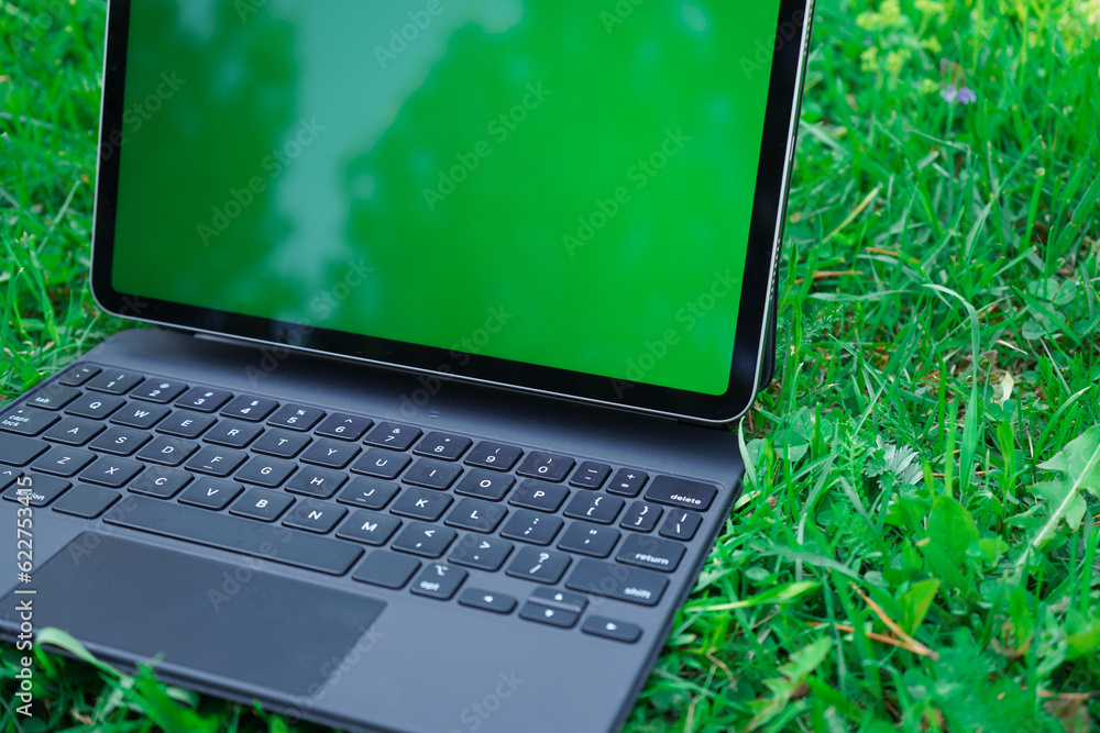 Digital tablet with green screen lying on the green grasses Digital tablet with green screen lying on the green grasses