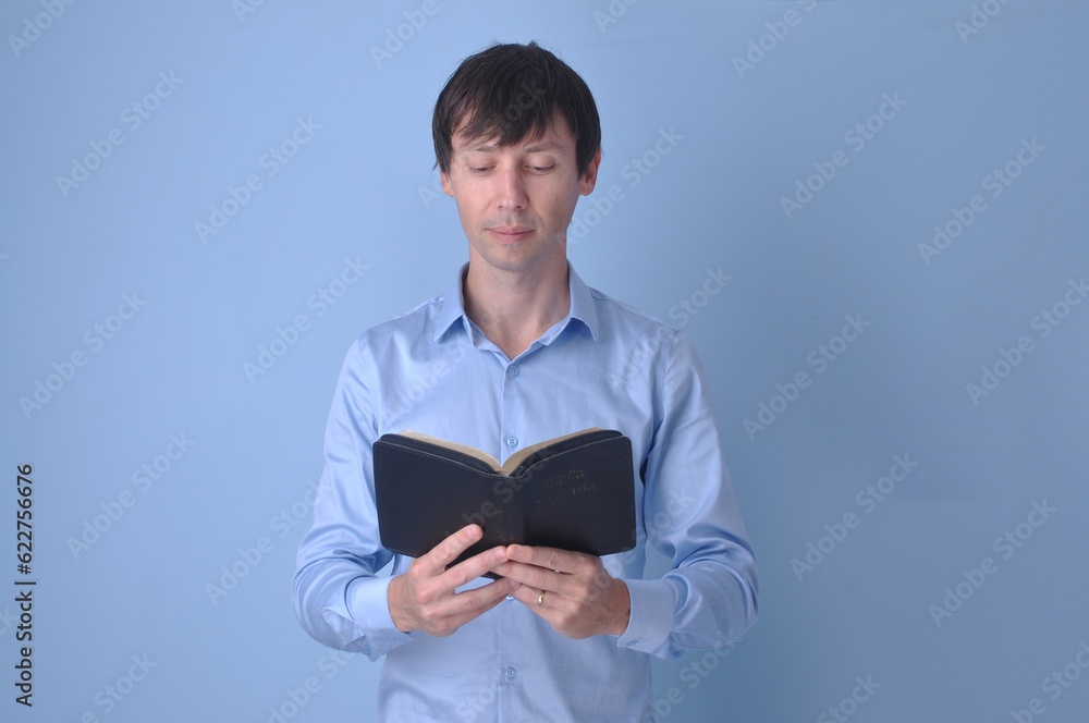 Jovem bonito vestindo suéter casual sobre fundo azul rosto olhando para a câmera. Pessoa positiva, cristão com biblia sagrada nas mãos Jovem bonito vestindo suéter casual sobre fundo azul rosto olhando para a câmera. Pessoa positiva, cristão com biblia sagrada nas mãos