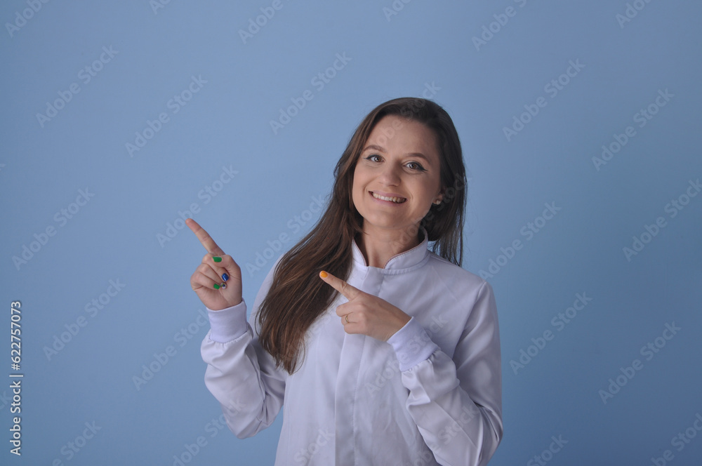 médica jovem sorridente usando uniforme branco em fundo azul, expressão feliz apontando para anúncio ou promoção médica jovem sorridente usando uniforme branco em fundo azul, expressão feliz apontando para anúncio ou promoção