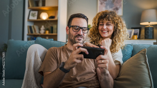 couple man and woman husband wife play smart phone video games at home