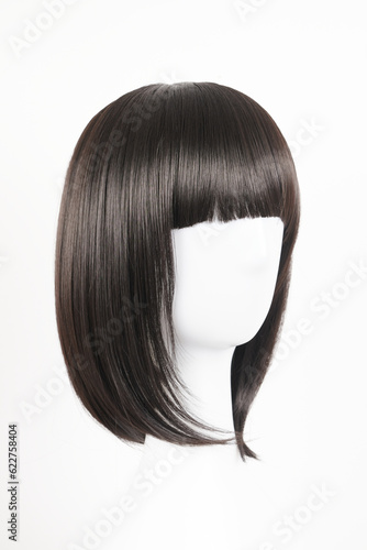 Natural looking black wig on white mannequin head. Medium length straight hair with bangs on the metal wig holder isolated on white background, side view