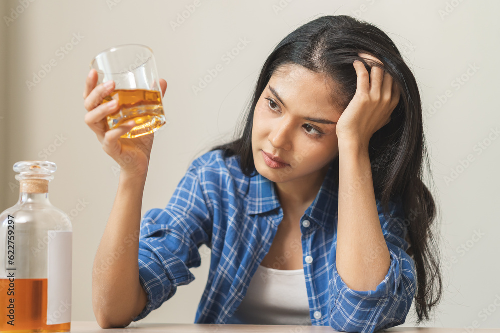 Alcoholism drunk asian young woman hand holding glass of alcohol or whiskey, female sitting alone, drinking on table at home, at night. Treatment of alcohol addiction, suffer abuse problem alcoholism Alcoholism drunk asian young woman hand holding glass of alcohol or whiskey, female sitting alone, drinking on table at home, at night. Treatment of alcohol addiction, suffer abuse problem alcoholism