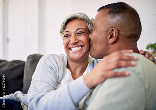 Love kiss, face and elderly couple happiness, romantic bond and enjoy quality time together, smile and retirement wellness. Living room sofa, care and senior man, old woman or people happy at home © Theron/peopleimages.com