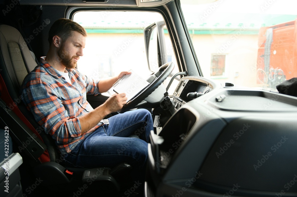 Side view of professional driver behind the wheel in truck's cabin. Side view of professional driver behind the wheel in truck's cabin.