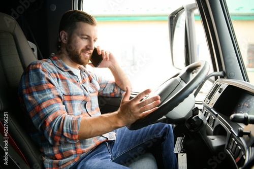 Young professional driver communicating over mobile phone while driving a truck.