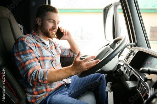 Young professional driver communicating over mobile phone while driving a truck. photo