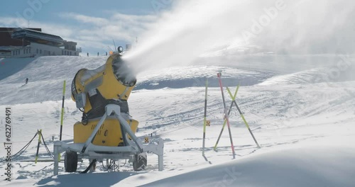 Snowmaking snow gun next to ski piste, during Winter. Ski resort, artificial snow, slope. photo
