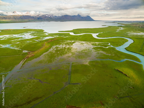 Aerial view of meadows with horses and a small winding river flowing into Borgarfjordur fjord, Vesturland, Iceland. photo