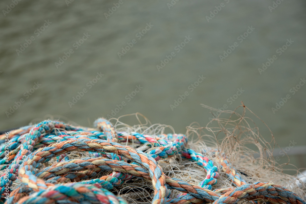 Pile of fishing rope and nylon netting. Close up view of fishing net agains sea