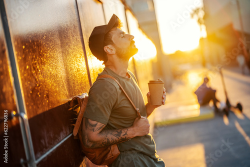 A man on the street is enjoying his takeaway coffee.